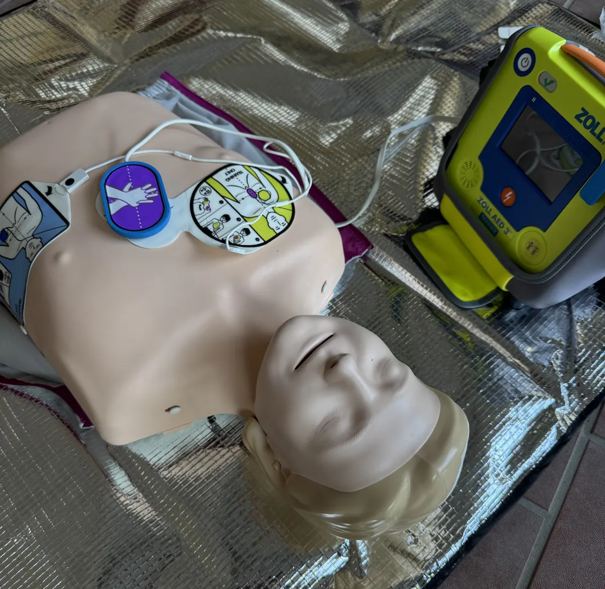 Reanimationsphantom mit aufgeklebten Übungselektroden und AED-Trainer.