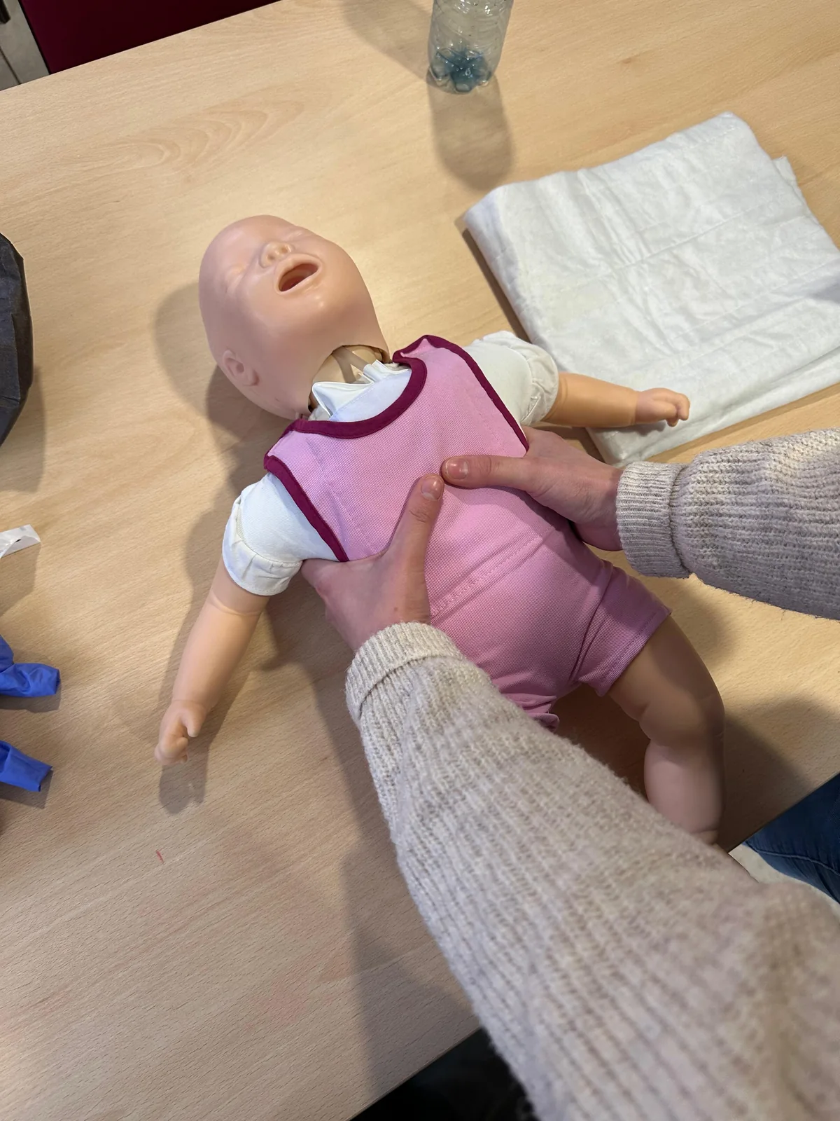 Teilnehmende Person übt die Wiederbelebung an einer Babypuppe.