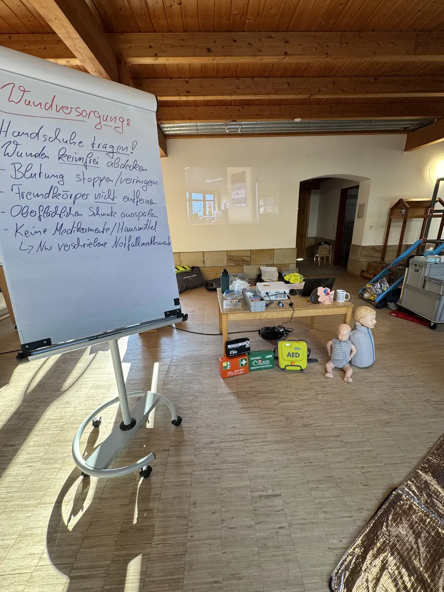 Vorbereiteter Kursraum mit Flipchart, Baby- und Kinderphantom sowie AED-Trainer.