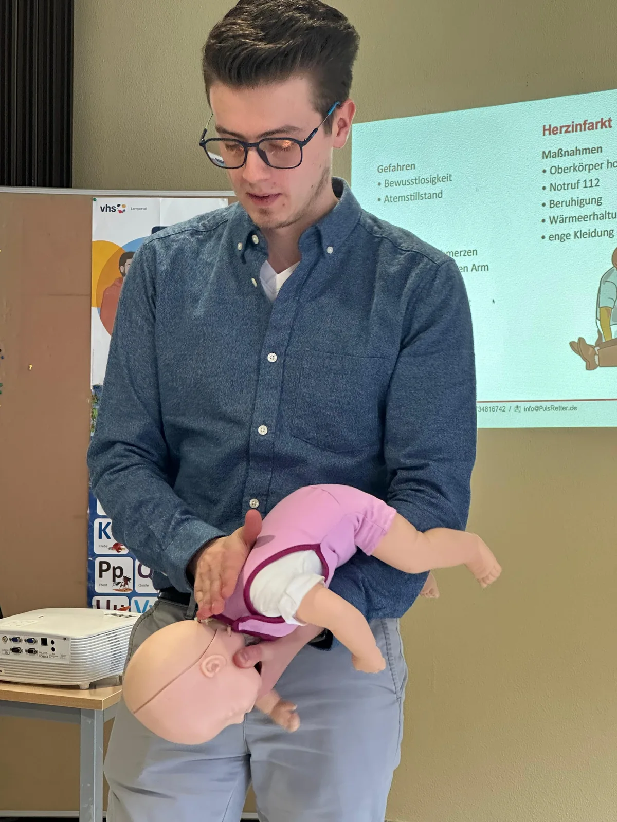 Samuel demonstriert eine Übung zum Verschluckungsnotfall mit einer Babypuppe.