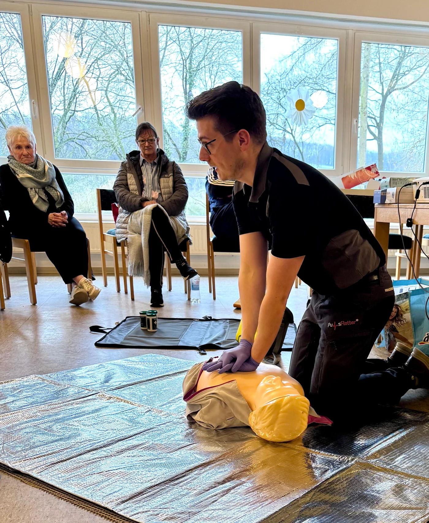 PulsRetter®-Dozent demonstriert die Herzdruckmassage an einer Übungspuppe vor Ehrenamtlichen der Zeitspende in Vlotho.